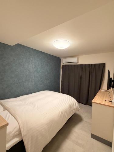 a bedroom with a white bed and a blue wall at hotel LUNA STELLA in Sendai