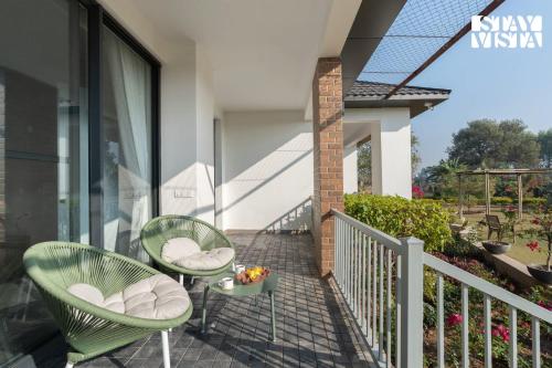 a patio with two chairs and a table on a balcony at StayVista at Treeansh with Pool, Lawn in Mohali