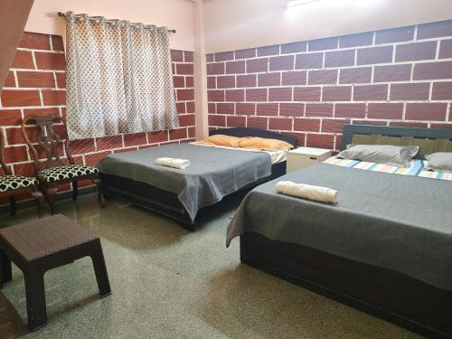 ein Schlafzimmer mit zwei Betten und einer Ziegelwand in der Unterkunft Canara Highway Home Stay in Ankola