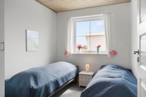 two beds in a small bedroom with a window at 323-Harboore-Skalvej-4-a in Harboør