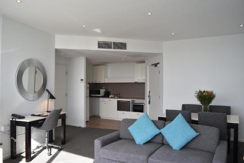 a living room with a couch and a table with blue pillows at Mantra Quayside Port Macquarie in Port Macquarie