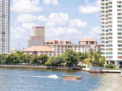 a boat in the water in front of a city at Ibis Bangkok Riverside in Bangkok