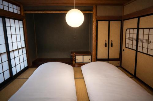 Zimmer mit 2 Betten und einer Leuchte in der Unterkunft 古民家 環水公園徒歩8分 閑静な住宅街 ドライブ旅行 近隣駐車場あり in Toyama