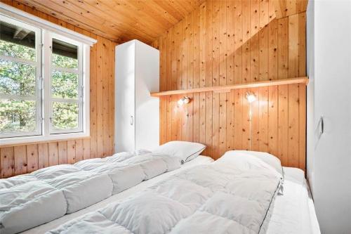 een rij witte bedden in een kamer met houten wanden bij 0018-Romo-Trinnesvej-16 in Bolilmark