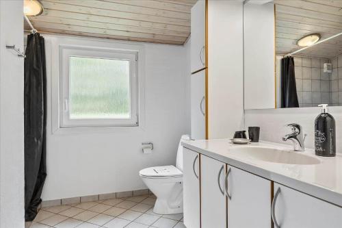 een badkamer met een wastafel en een toilet en een raam bij 0001-Romo-Blabaervej-23 in Bolilmark