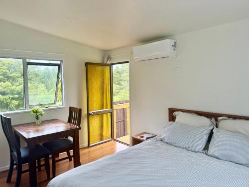 een slaapkamer met een bed, een bureau en ramen bij Green View Retreat in Whangarei
