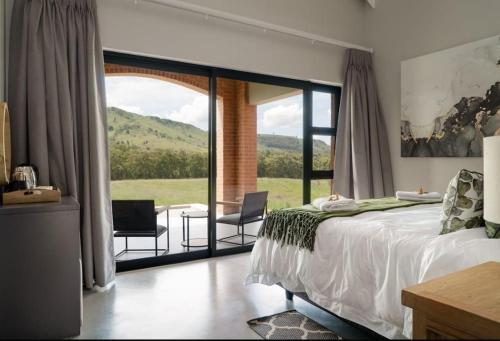 una camera da letto con un letto e una grande finestra di vetro di Highland gate Golf estate Mountain view 780 a Dullstroom