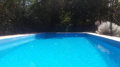 een groot zwembad van blauw water in een tuin bij Los Damascos in Merlo