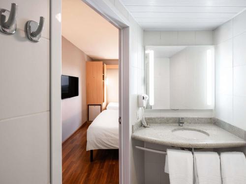 a bathroom with a sink and a bed at ibis Ourinhos in Ourinhos