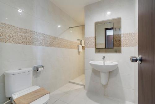 a bathroom with a toilet and a sink and a mirror at Life The One Makassar in Makassar