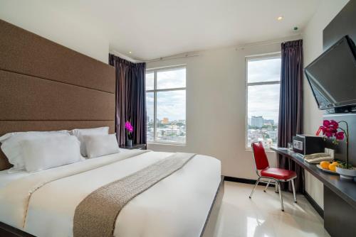 a bedroom with a bed and a desk with a television at Life The One Makassar in Makassar