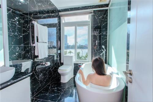 een vrouw in een bad in een badkamer bij Palmier Hotel - Art House Da Nang in Da Nang