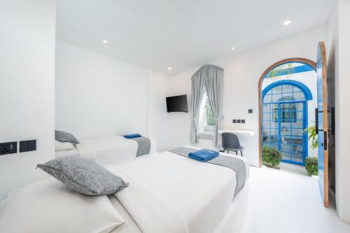 a white bedroom with two beds and a window at Bombora Surf Camp in Uluwatu