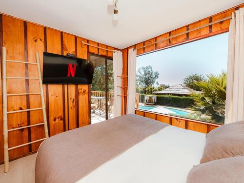 a bedroom with a bed and a large window at Pao Pao Lodge Algarrobo in Algarrobo