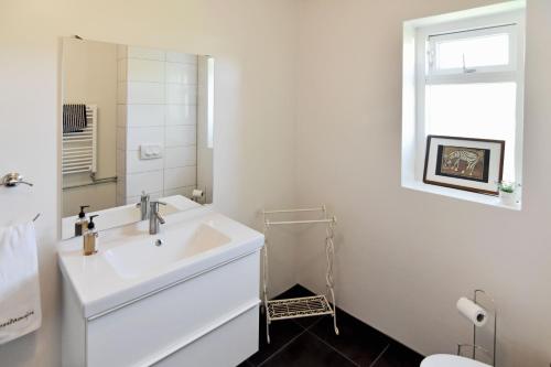 a white bathroom with a sink and a mirror at Breidamyri Farm Apartments in Laugar
