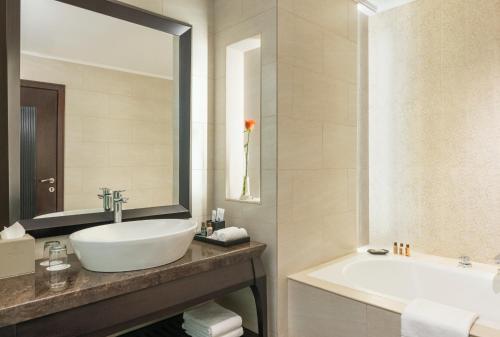 a bathroom with a sink and a tub and a mirror at Sheraton Sharjah Beach Resort and Spa in Sharjah