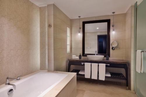 a bathroom with a tub and a sink and a mirror at Sheraton Sharjah Beach Resort and Spa in Sharjah