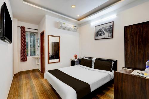 ein Schlafzimmer mit einem großen weißen Bett und einem Fernseher in der Unterkunft Super Townhouse Auroville Beach Formerly De Heritage in Kottakupam