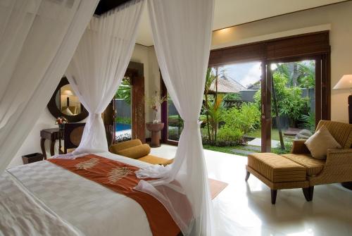 a bedroom with a bed and two chairs and a window at Bumi Linggah Villas Bali in Sukawati