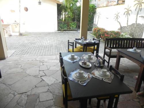 a table and chairs with dishes on them on a patio at Pousada Tropicalia in Itaparica Town