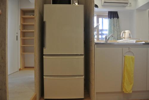 a refrigerator in a kitchen next to a sink at Backpackers Hotel NOOSA JAPAN in Takatsuki Tonda in Takatsuki