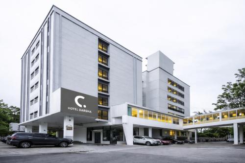 an office building with cars parked in a parking lot at C Hotel Bangna in Bangkok