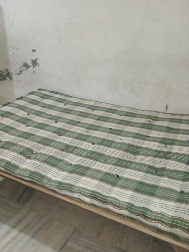 a bed with a green and white blanket on the floor at josh poonam in Prayagraj
