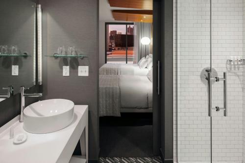a bathroom with a sink and a shower with a bed at Le Meridien Columbus, The Joseph in Columbus