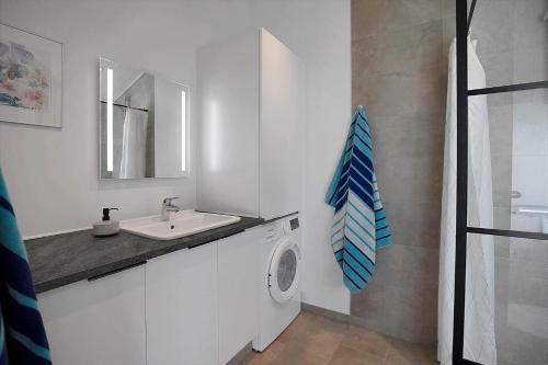 een witte badkamer met een wastafel en een wasmachine bij 10070-Rorvig-Kirkestien-25 in Rørvig