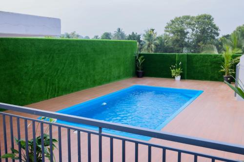 a swimming pool on a balcony with a green hedge at Munderi Green Mounts - Family Rooms with Pool, Wayanad, Kalpetta in Kalpetta