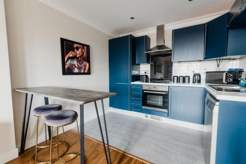 a blue kitchen with a table and two stools at Hullidays - King & Queen Ensuite in Hull