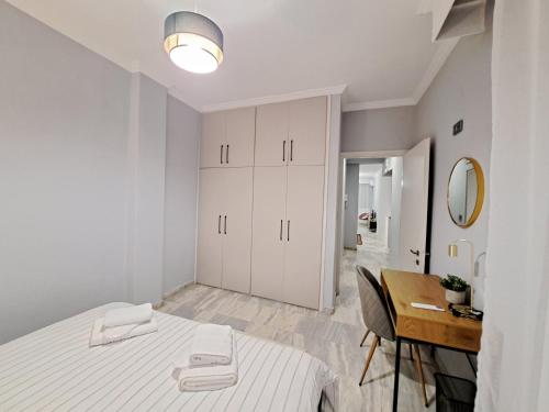 a white bedroom with a bed and a desk at Twins Apartments 2 in Serres