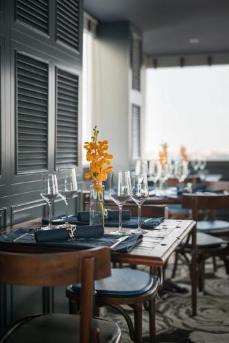a table with glasses and a vase with flowers on it at La Nueva Boutique Hotel Hanoi & Spa in Hanoi