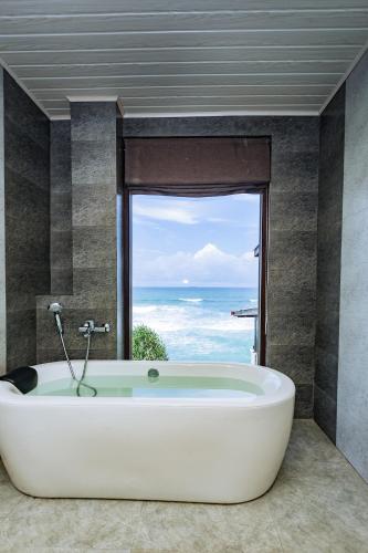 a bath tub in a bathroom with a view of the ocean at Beach & Bliss Mirissa in Mirissa
