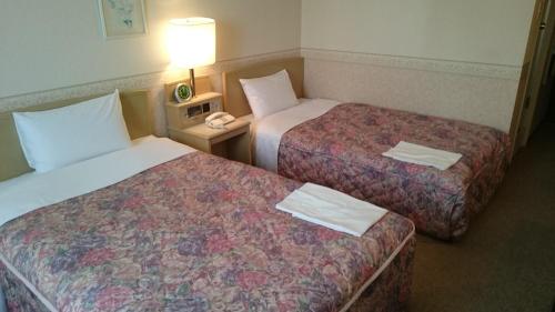 a hotel room with two beds and a lamp at Hotel Crown Hills Kanazawa in Kanazawa