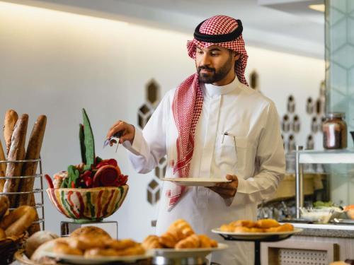 Ein Mann in einer Küche mit einem Teller Essen. in der Unterkunft ibis Styles Makkah in Mekka