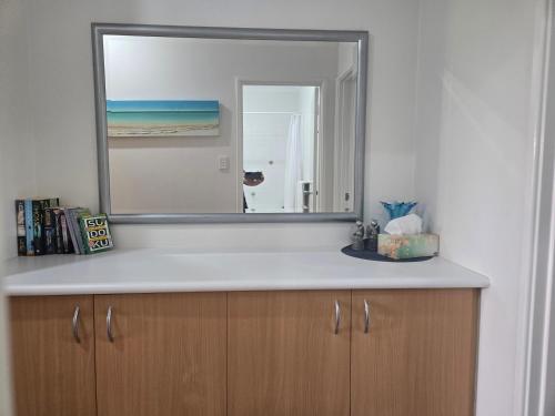 einen Spiegel auf einem Holzschrank im Bad in der Unterkunft Waterfront Hideaway with Pool, Spa & BBQ Area jetty available in Mandurah