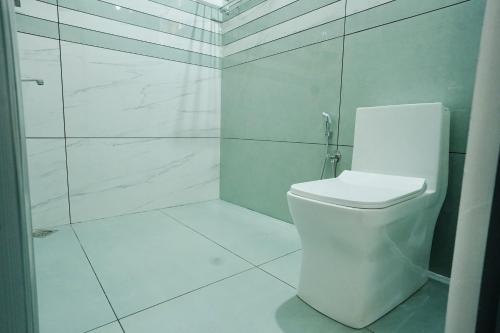 a white bathroom with a shower and a toilet at Mermaid Marari in Mararikulam