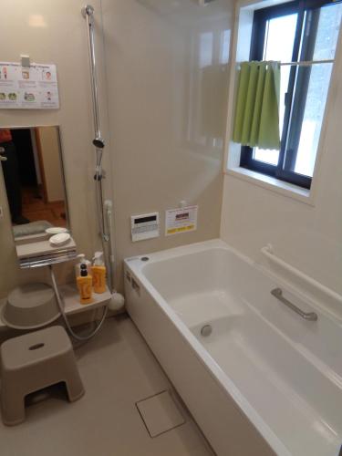 a white bathroom with a tub and a window at Premium Guest House Alaskan Dream in Akiota