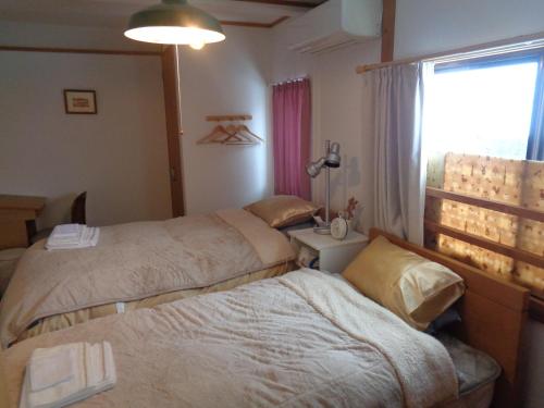 a hotel room with two beds and a window at Premium Guest House Alaskan Dream in Akiota