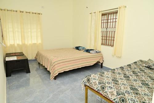 a bedroom with two beds and a window at Cheenu Cottage in Yelagiri