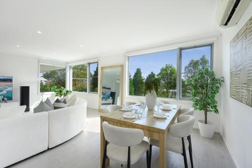 une salle à manger avec une table et des chaises blanches dans l'établissement Self-Contained 3BR Upper-Level Unit Collaroy, à Collaroy