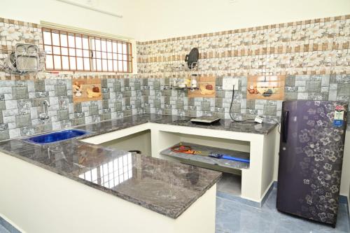 a kitchen with marble counter tops and a refrigerator at Cheenu Cottage in Yelagiri