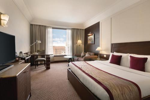 a hotel room with a large bed and a desk at Ramada Plaza by Wyndham JHV Varanasi in Varanasi