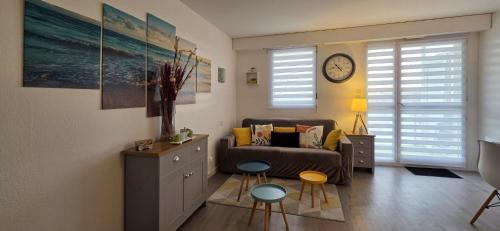 ein Wohnzimmer mit einer Couch und zwei Hockern in der Unterkunft ESCAPADE FAMILIALE A LA MER in Quiberon