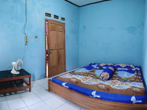 a bedroom with a bed and a blue wall at BATUKARAS Orchid Homestay in Batukaras