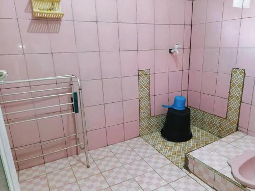 ein rosa Badezimmer mit einem blauen Hut auf dem Boden in der Unterkunft BATUKARAS Orchid Homestay in Batukaras