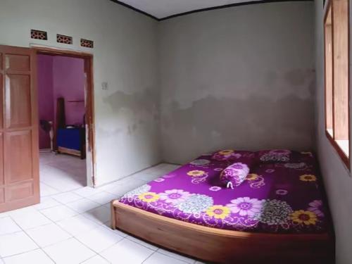 ein Schlafzimmer mit einem lila Bett mit Blumen darauf in der Unterkunft BATUKARAS Orchid Homestay in Batukaras