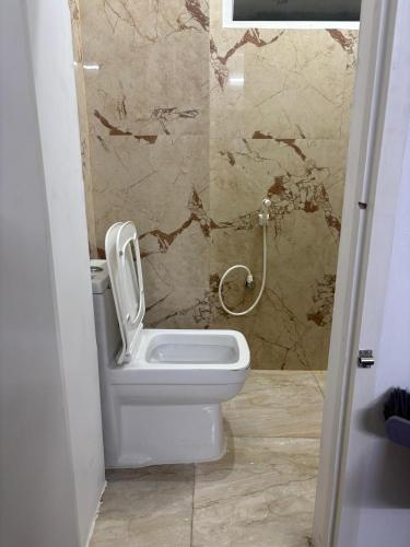a white toilet in a bathroom with a wall at Varson Stay in Pondicherry