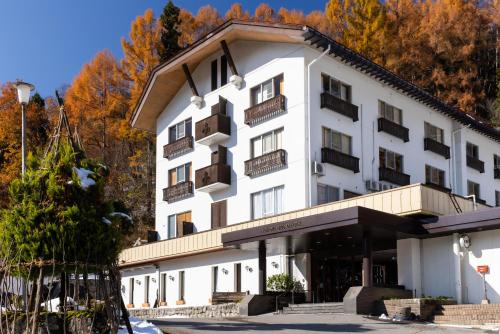 a large white building with balconies and trees at Nozawa Grand Hotel in Nozawa Onsen